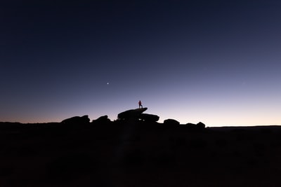 夜间站在岩石上的人的剪影